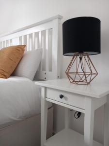 a bed with a white table with a lamp on it at NEW TO MARKET - Spectre Home, Hatfield - Contractors, Engineers, Relocators, LongStay Discounts, Parking in Hatfield