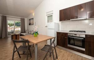 eine Küche mit einem Tisch, Stühlen, einem Herd und einem Kühlschrank in der Unterkunft Apartmani Valentina Drvenik in Drvenik