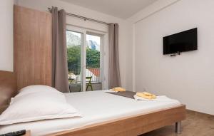 a bedroom with a bed with a flat screen tv at Apartmani Valentina Drvenik in Drvenik