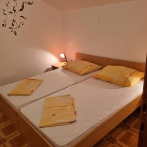 a bedroom with a large bed with white sheets and yellow pillows at Apartments Nada in Vir
