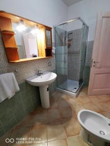 une salle de bain avec un lavabo et une douche en verre dans l'établissement Le castellane, à Castelsardo