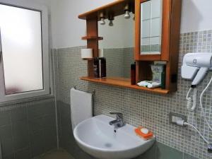 une salle de bains avec un lavabo et un miroir dans l'établissement Le castellane, à Castelsardo 83 autres photos