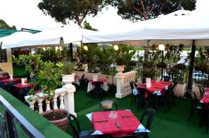 an outdoor restaurant with red tables and white umbrellas at Fortuna Village Pompei in Pompei