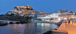 un groupe de personnes marchant sur une plage avec une montagne dans l'établissement Le castellane, à Castelsardo
