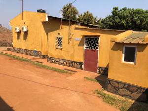 a yellow building with a red door on a dirt road at Residencial Meu Tio in Chimoio