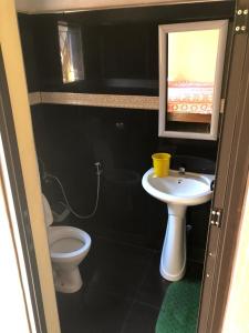 baño con lavabo y aseo y ventana en Residencial Meu Tio, en Chimoio