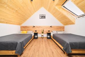 two beds in a room with wooden ceilings at Baza Dunajec Komfortowy Domek in Czarny Dunajec