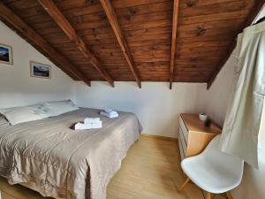 een slaapkamer met een bed, een stoel en houten plafonds bij Yellow House Cottage in El Chalten