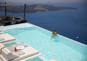 una persona in una piscina in acqua di Dana Villas & Infinity Suites a Firostefani