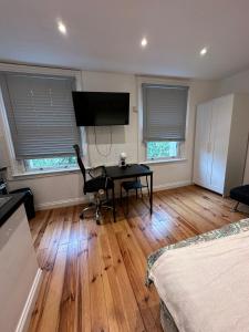 a living room with a desk and a television at Notting Hill Guest Studio in Ealing