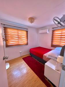 a bedroom with a red bed and two windows at Two-Bedroom Townhouse Camella Bacolod South in Bacolod