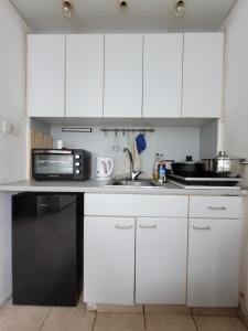 a kitchen with white cabinets and a microwave at סטודיו על הים in Bat Yam
