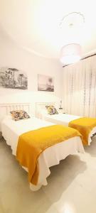 フエンカリエンテ・デ・ラ・パルマにあるApartamentos Los Volcanesの白い部屋のベッド2台(黄色のシーツ付)