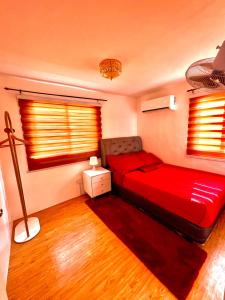a bedroom with a red bed and two windows at Two-Bedroom Townhouse Camella Bacolod South in Bacolod