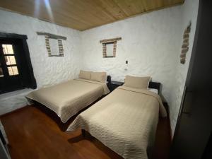 two beds in a room with white walls and windows at Hotel Colonial Centro Historico in Tunja