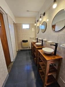 een badkamer met 3 wastafels en 2 spiegels bij Yellow House Cottage in El Chalten