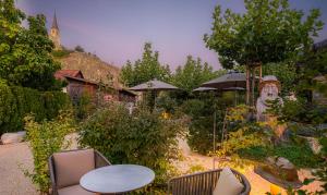 a garden with tables and chairs and umbrellas at Kapitel 7 Boutique-Hotel in Raron