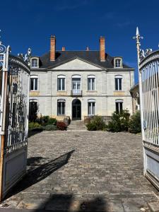 une grande maison blanche avec un portail en face de celle-ci dans l'établissement La Parenthèse Fléchoise, Chambre Armand, à La Flèche