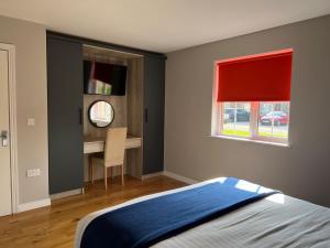 1 dormitorio con cama, escritorio y ventana en Stable Court Apartments, en Antrim