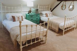 a bedroom with two beds and a green dresser at Laundry Cottage in Loughborough