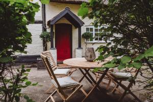 une table et des chaises devant une maison avec une porte rouge dans l'établissement Laundry Cottage, à Loughborough