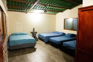a room with two beds and a table in it at Cabaña Casa Lila in Santa Marta