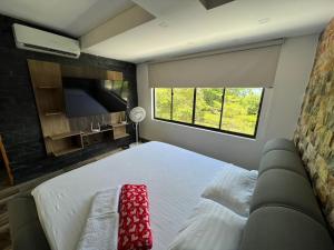 ein Schlafzimmer mit einem Bett, einem Sofa und einem TV in der Unterkunft Hermosa cabaña en sopetran in Sopetran