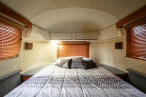 a bedroom with a large bed in a room with windows at Big Texan Airstream in Amarillo