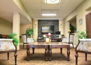 a lobby with a table and chairs and a tv at The Medicine Hat Villa in Medicine Hat