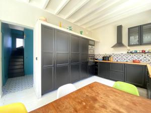 a kitchen with black cabinets and a wooden table at Agréable villa à Pyla plage in La Teste-de-Buch