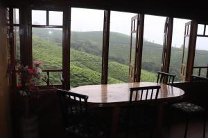 a table and chairs in a room with a view at spice garden Resorts munnar in Anachal