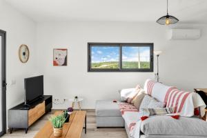 uma sala de estar branca com um sofá e uma televisão em Apartamento Campo e praia em Aljezur