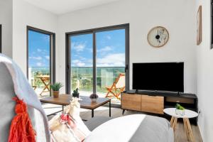 a living room with a flat screen tv and large windows at Apartamento Campo e praia in Aljezur