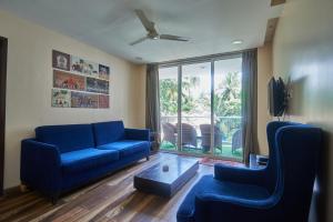a living room with blue couches and a large window at Eternal wave by HappyInch in Calangute