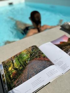 a book sitting on a table next to a swimming pool at Casas do Patio Country Houses & Nature in Caldas da Felgueira