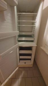 un réfrigérateur vide avec une porte ouverte dans une pièce dans l'établissement Gemütliche Monteurwohnung in Sandersdorf bis 6 Personen, à Sandersdorf