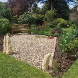 a garden with a bench and a gravel yard at Bracken Lodge in Merston
