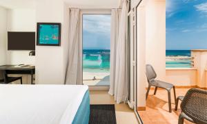 a bedroom with a bed and a view of the beach at Hotel Tahiti in Es Pujols