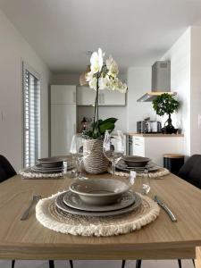 a table with plates and glasses and a vase of flowers at Magnifique appartement à la frontière suisse in Saint-Louis