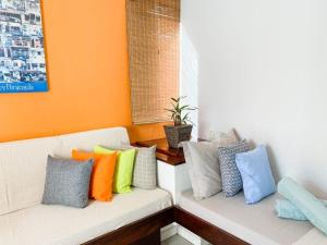 um sofá branco com almofadas coloridas em Apto Praia de Mariscal e Canto Grande Bombinhas SC - Canela Flats 02 em Bombinhas