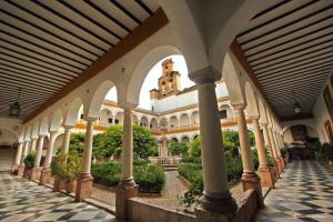 APARTMENT EL LLANO في لوسينا: مبنى به اعمدة وساحة بها نباتات
