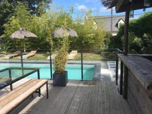 a wooden deck with a bench and a swimming pool at Les logis du forgeron, Gites de groupe entre Loire & vignes in Saint-Jean-des-Mauvrets