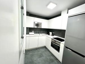 uma pequena cozinha com armários brancos e um frigorífico em APARTMENT EL LLANO em Lucena