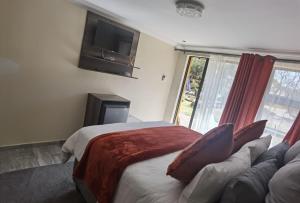 a bedroom with a bed and a couch and a tv at Lasev Resort in Pretoria