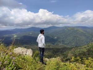 um homem parado no topo de uma montanha olhando para as montanhas em Heritage Homestay em Chikmagalūr