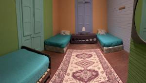 a room with three beds and a table with a rug at Kom Hostal in Pichilemu
