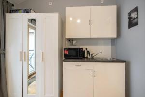 uma cozinha com armários brancos e um micro-ondas em Private Retreat Close to Stations in Praha 3 em Praga