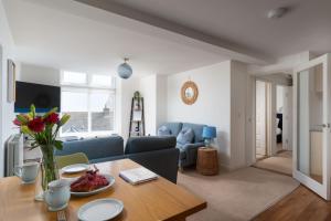 a living room with a table and a blue couch at Après Beach Apartment Sleeps 4 Penzance in Penzance