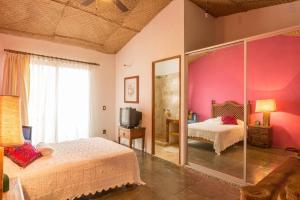 プエルト・バジャルタにあるCasa La Columnaのピンクの壁のベッドルーム1室(ベッド2台付)