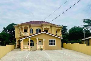 une maison jaune avec une clôture devant elle dans l'établissement The Rest Stop- Gated Community-24 Hrs Security, à Montego Bay